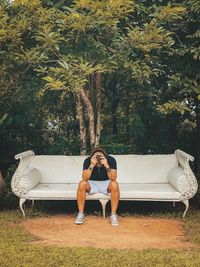 Man sitting on sofa against trees