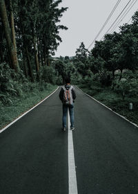 Rear view of people walking on road amidst trees