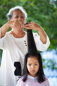 Grandmother cutting girl hair
