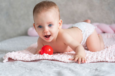 Portrait of cute baby boy sitting on bed at home