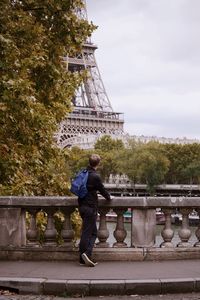 Man looking eiffel tower while standing on footpath