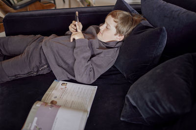 Boy lying on sofa and using cell phone