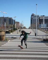 Young man skateboarding on road in city