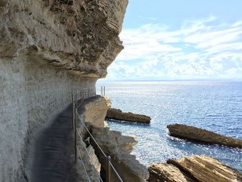 Scenic view of sea by cliff against sky