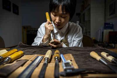 Young chinese violin maker at work in her workshop