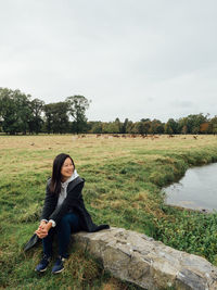 Full length of woman sitting by plants against sky