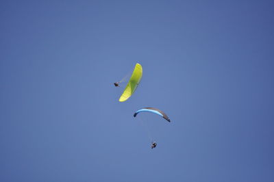 Low angle view of person paragliding against clear blue sky