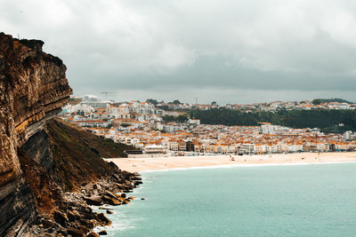 Scenic view of beach by city against sky