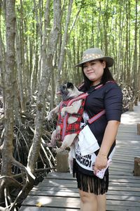 Portrait of woman standing amidst trees in forest