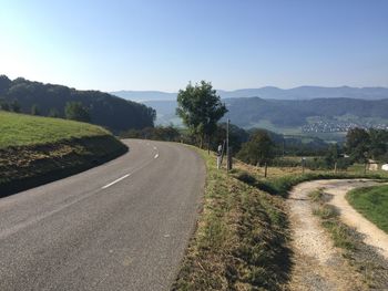 Road amidst green landscape against clear sky