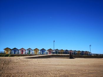 Buildings on beach against clear blue sky