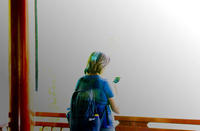 Rear view of woman standing against wall