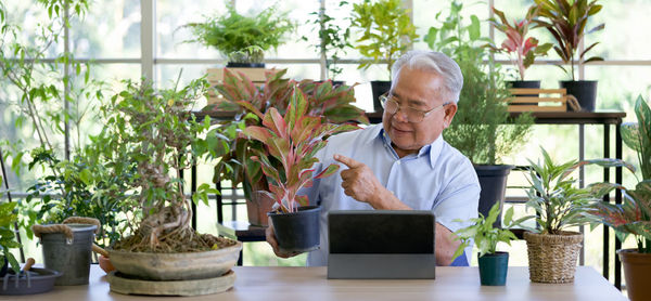 Midsection of man sitting by potted plants on table