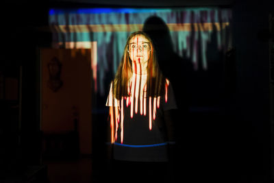 Mid adult woman standing in light reflection at home during pandemic