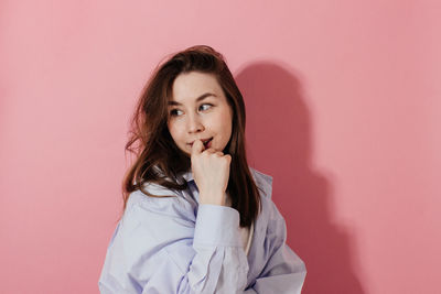 Portrait of woman standing against pink background