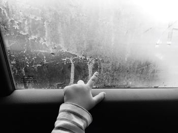 Cropped hand of child touching car window