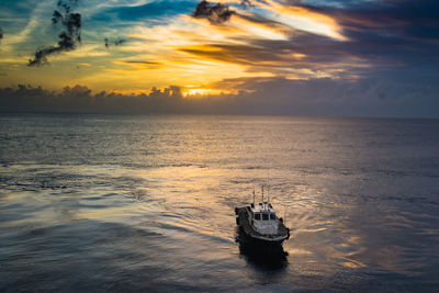 Boat sailing in sea against sunset 