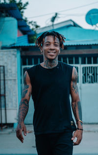 Portrait of smiling young man standing against built structure