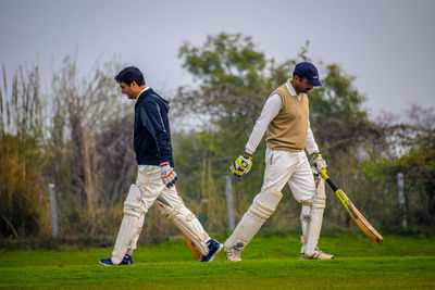 Rear view of men playing on golf course