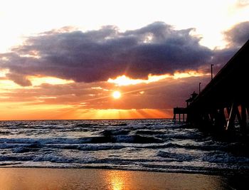 Scenic view of sea against cloudy sky during sunset