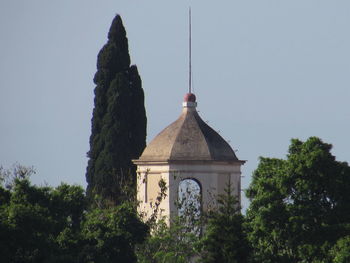 Cross against trees and building against sky