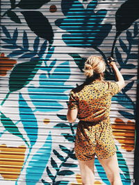 Rear view of woman standing against graffiti