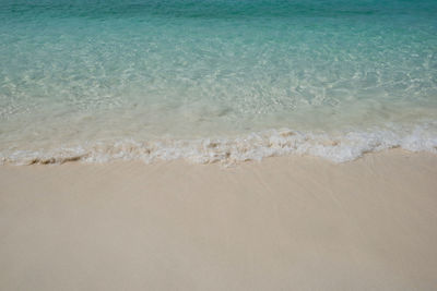 The blue andaman sea with the sea waves on white sand beach in bright daylight