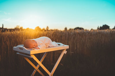 Man relaxing on field against sky during sunset