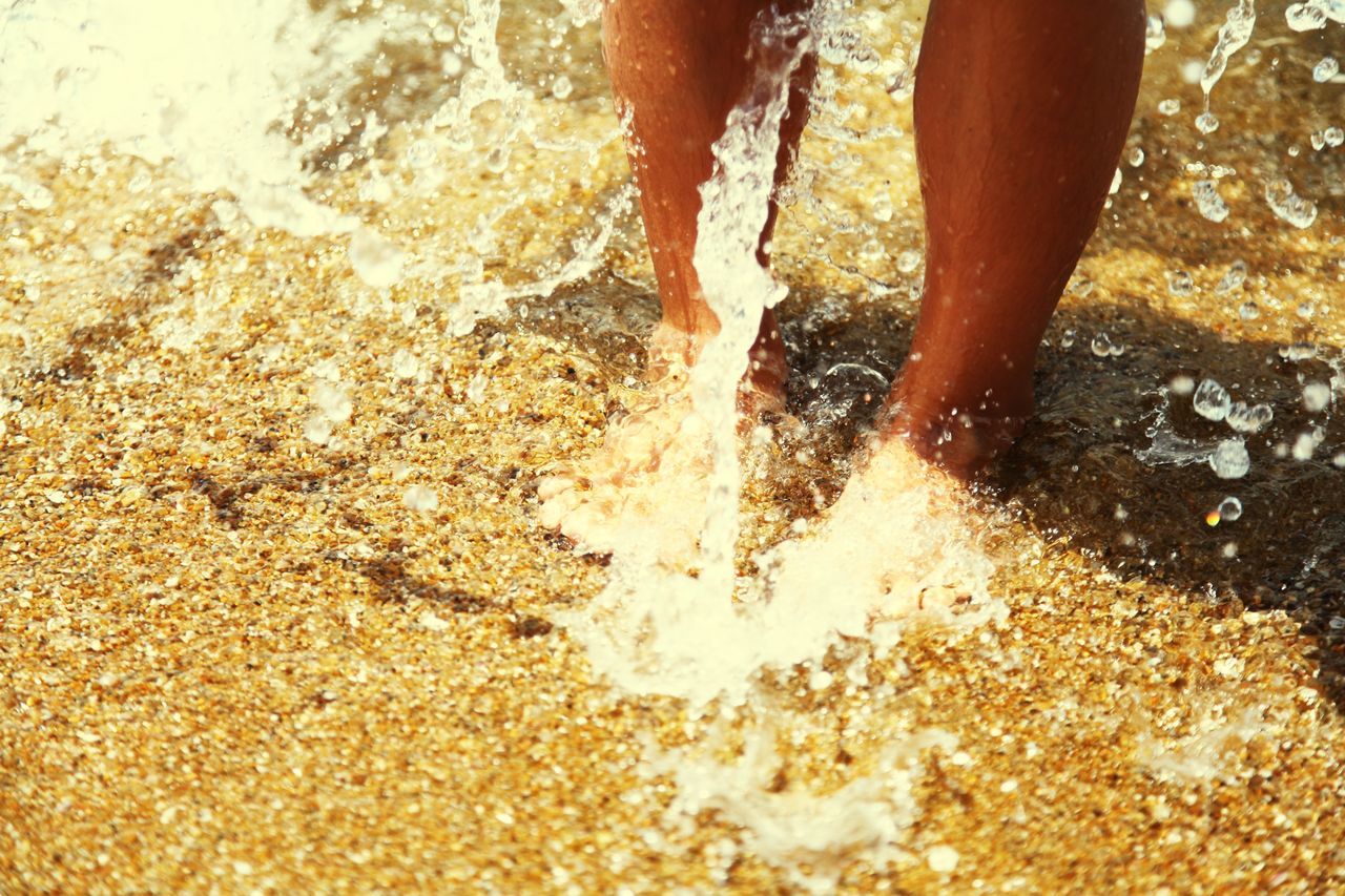 low section, person, water, human foot, beach, lifestyles, barefoot, standing, sand, leisure activity, sunlight, wet, part of, motion, unrecognizable person, close-up