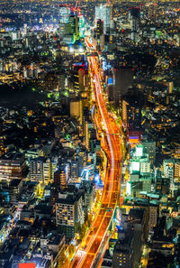 High angle view of illuminated street amidst buildings at night