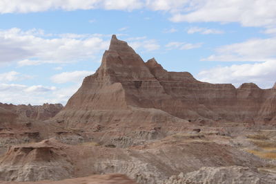 Rock formations on landscape against cloudy sky