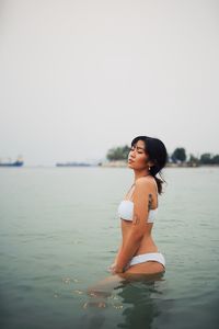 Side view of sensuous young woman wearing bikini in sea