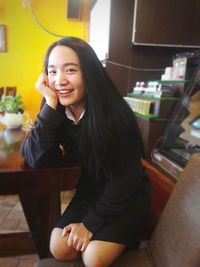 Portrait of smiling young woman sitting on mobile phone