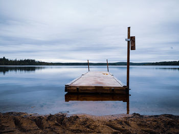 Wooden jetty in lake against sky