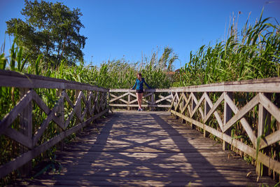 Woman standing on footbridge against crops at farm