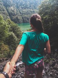 Rear view of woman standing amidst trees in forest