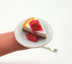 Close-up of hand holding strawberry over white background