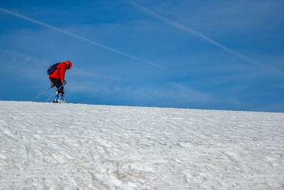 Man skking on snowcapped mountain against blue sky