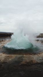 Water splashing on landscape against cloudy sky