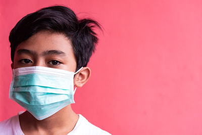 A boy wearing a t-shirt with a red background, wearing a medical face mask