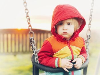 Portrait of cute girl sitting on swing in playground