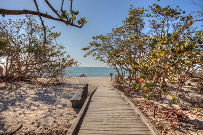 Boardwalk leading towards sea against sky