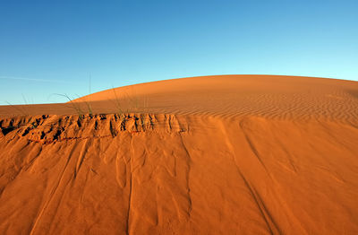 Sand dunes in desert against clear blue sky