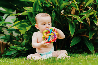 Cute baby girl playing with toy on field