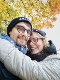 Portrait of couple smiling while standing against autumn tree