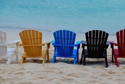 Empty chairs on beach against blue sky