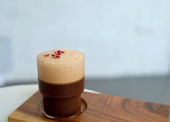 Ice coffee with dried rose on wooden trey.