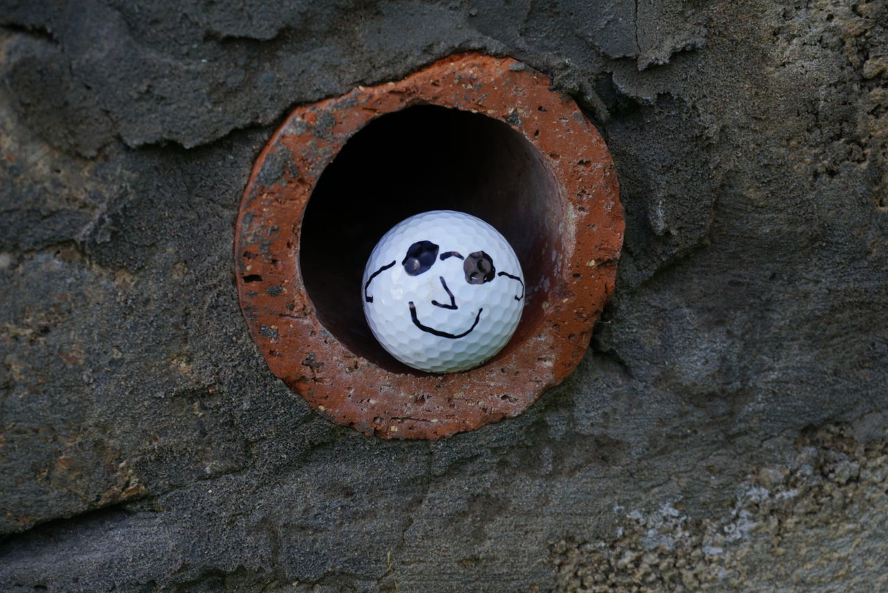 no people, face, anthropomorphic face, anthropomorphic, representation, hole, human representation, art and craft, creativity, anthropomorphic smiley face, close-up, male likeness, day, circle, smiling, craft, geometric shape, textured, outdoors, architecture