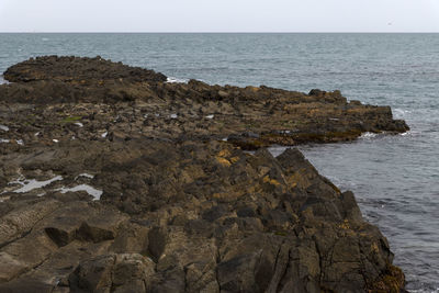 Rock formation on beach against sky