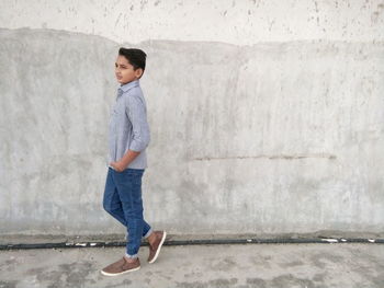 Teenage boy standing against concrete wall